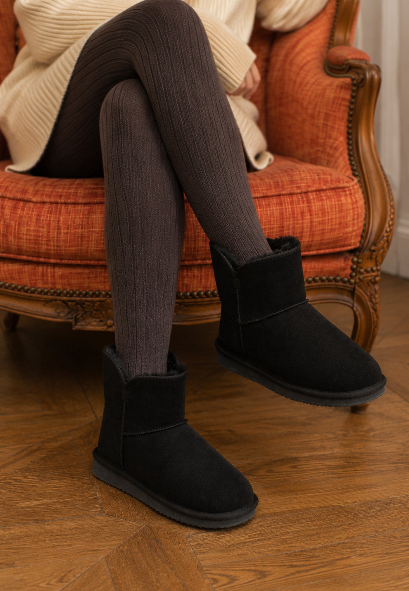 Bottines fourrées Bellevue noires portées assise, collants côtelés et fauteuil orange