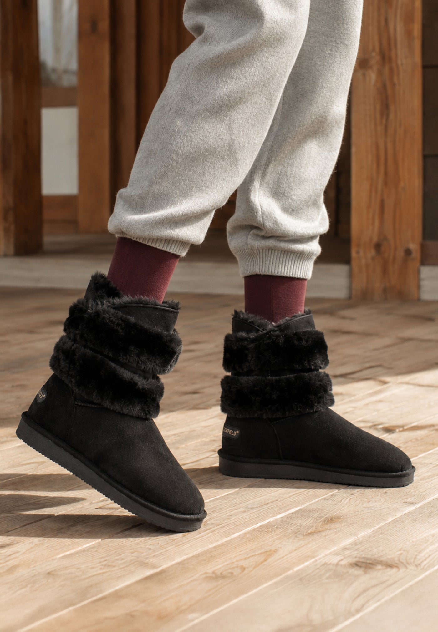 Paire de bottines fourrées Erie noires portées avec un jogging écru et des chaussettes bordeaux