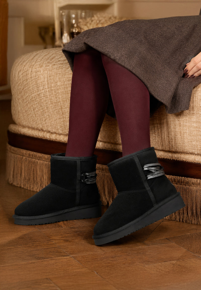 Bottines fourrées Dolce noires portées avec des collants bordeaux et une jupe