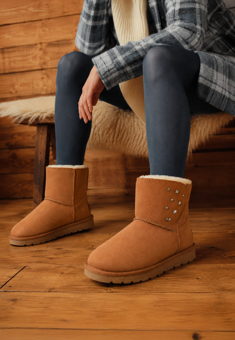 Assise sur un banc, bottines fourrées Lady camel portées avec un legging gris