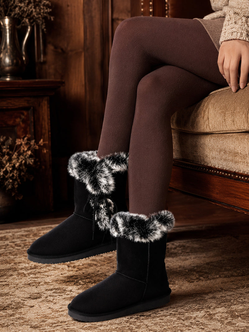 Bottines fourrées Coma noires portées avec des collants prune, assise sur un canapé beige