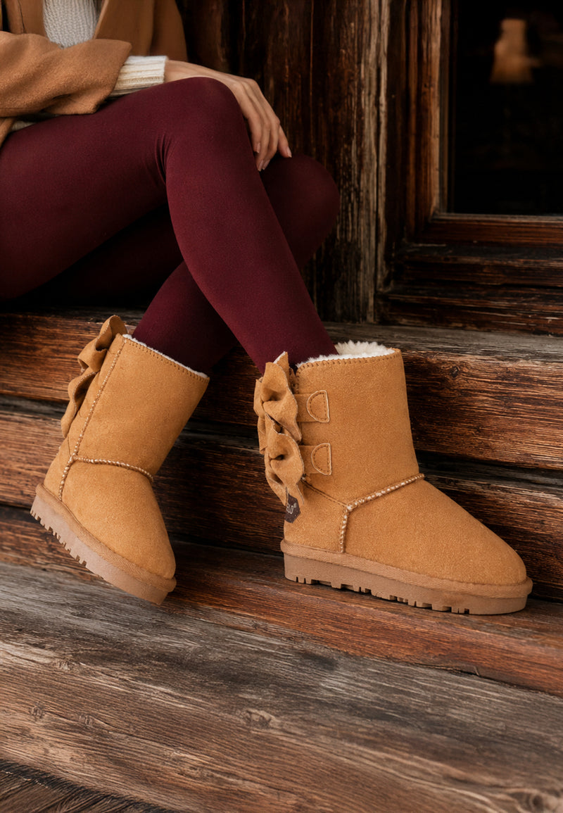 Bottines fourrées Belezza camel portées devant un chalet avec des leggings bordeaux