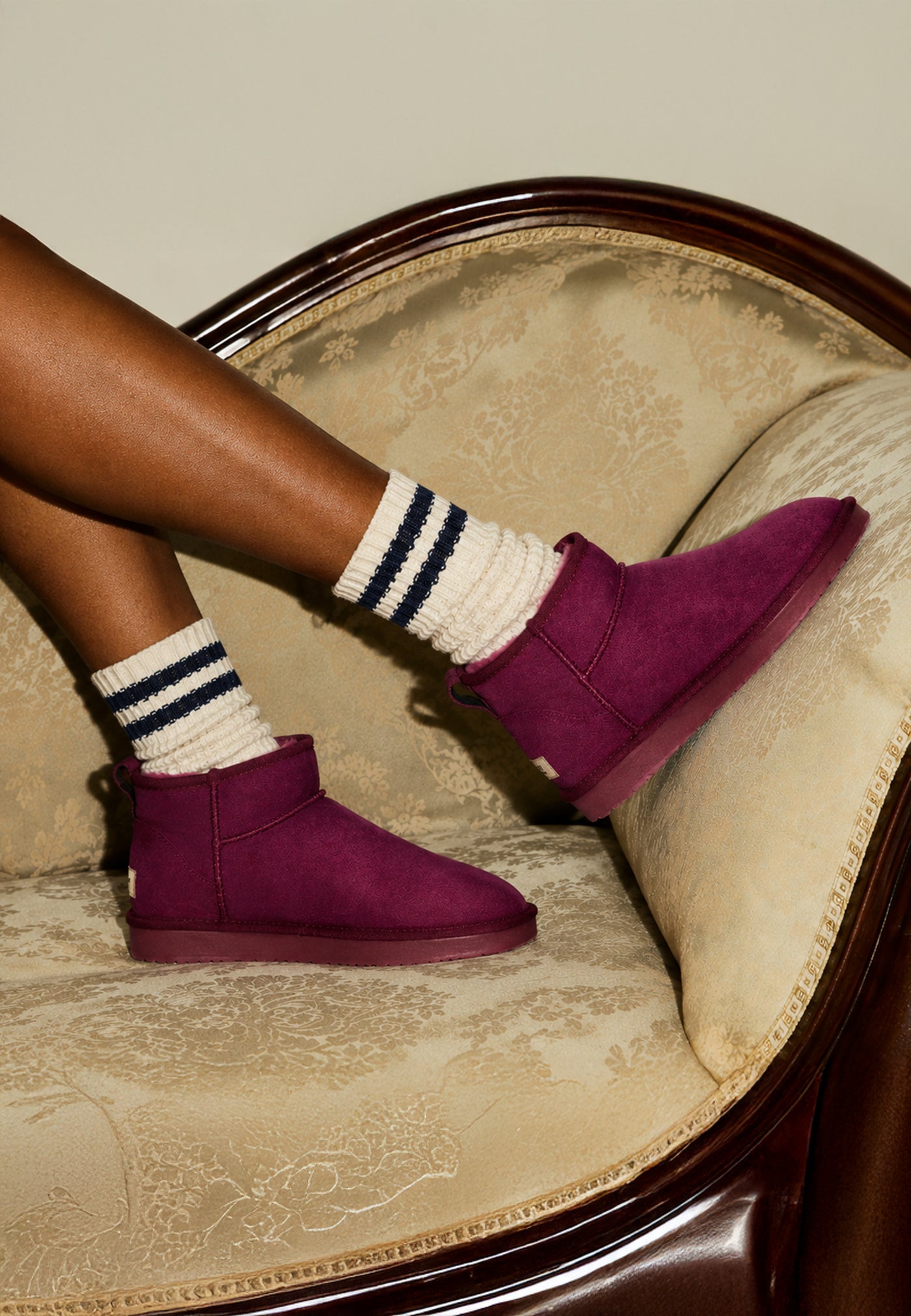Bottine fourrée Mini Milli bordeaux portée sur une méridienne damassée, chaussettes rayées