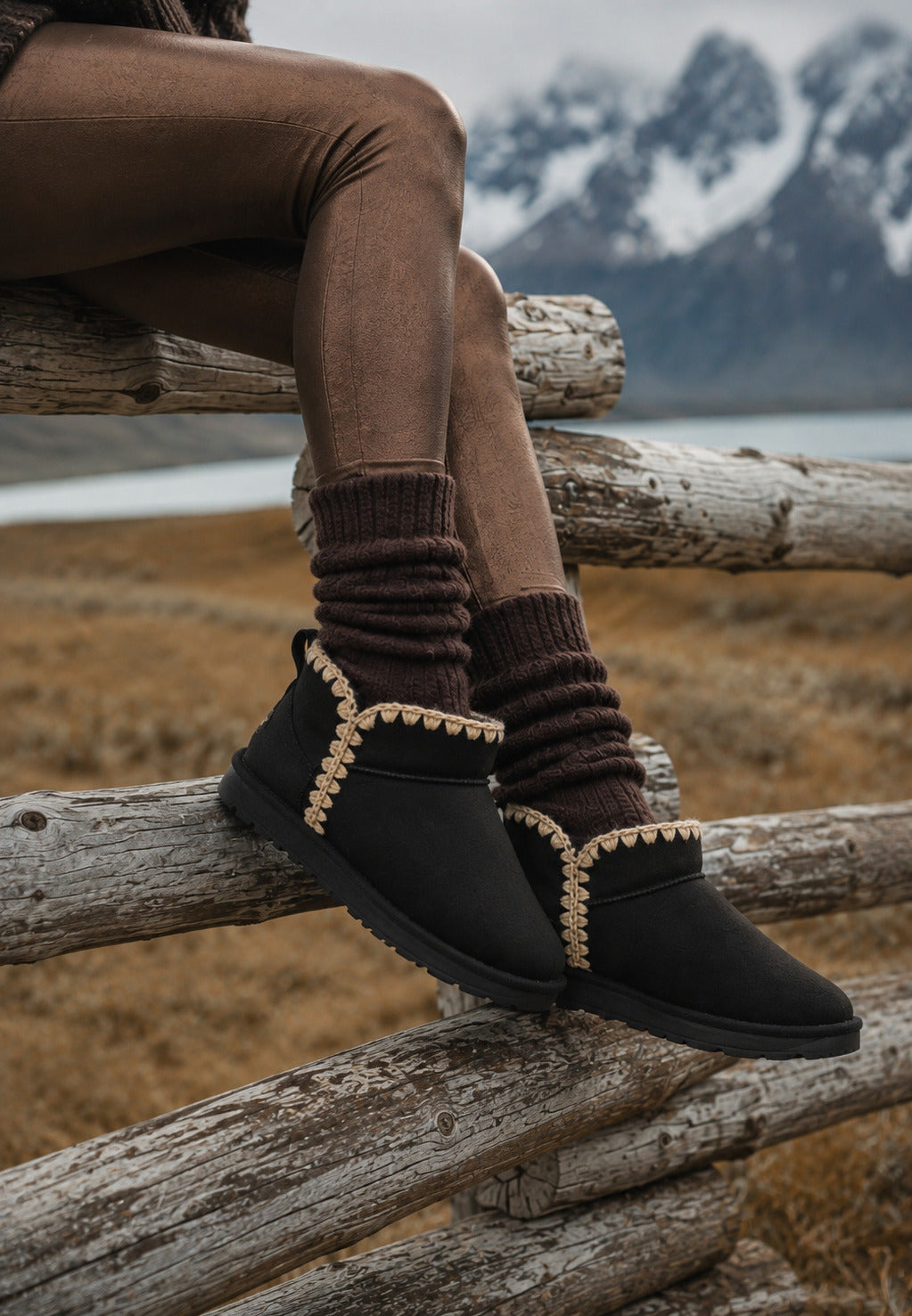 Bottines fourrées Bakelite noires portées sur une barrière de rondins en montagne