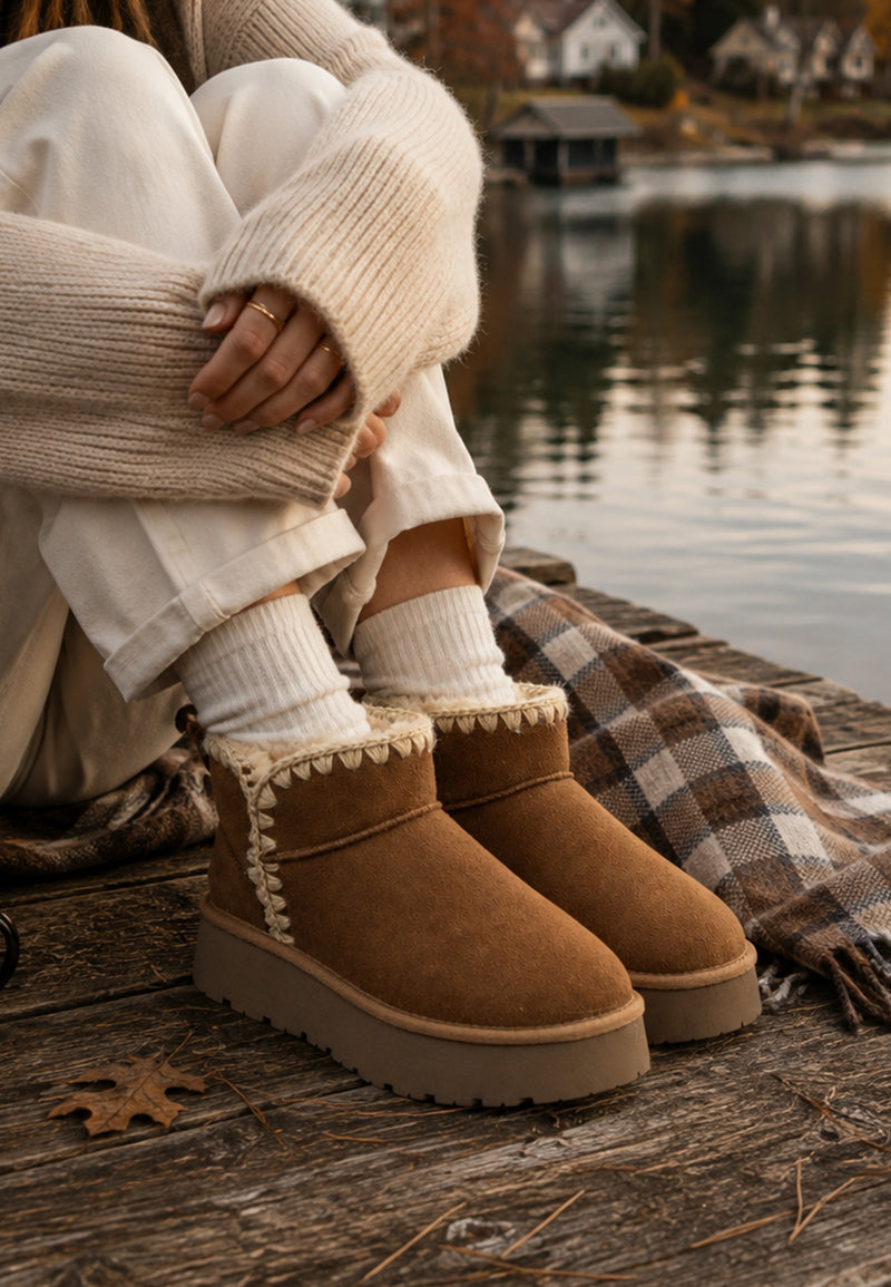 Bottines fourrées Baklava camel portées au bord d'un lac, avec chaussettes côtelées écrues