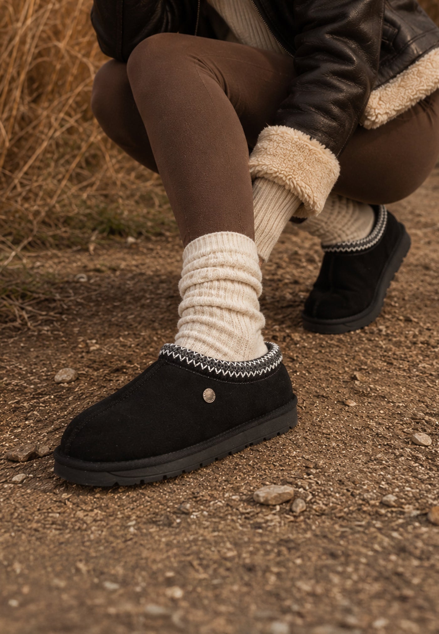 Bottines fourrées Bruce noires portées sur un chemin de terre, chaussettes écrues
